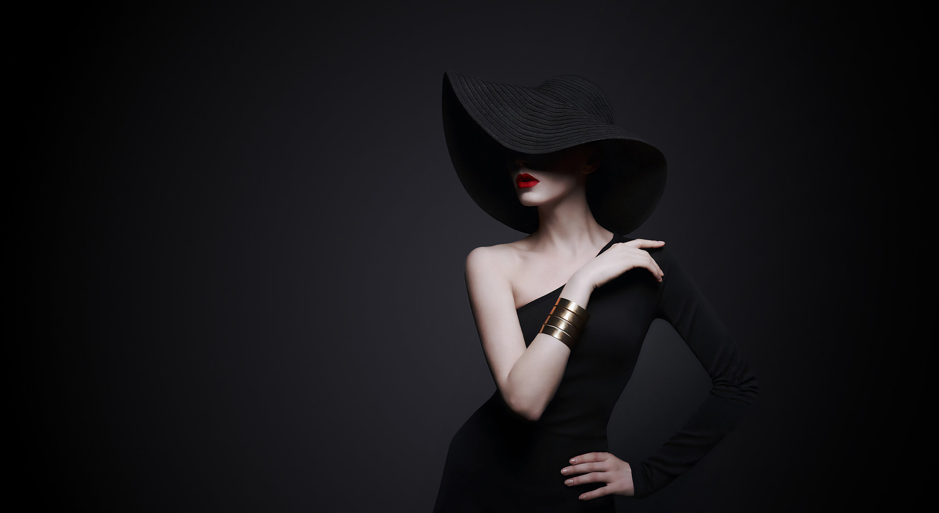 Frau mit rotem Lippenstift und schwarzem Kleid und Hut in einer eleganten Pose.